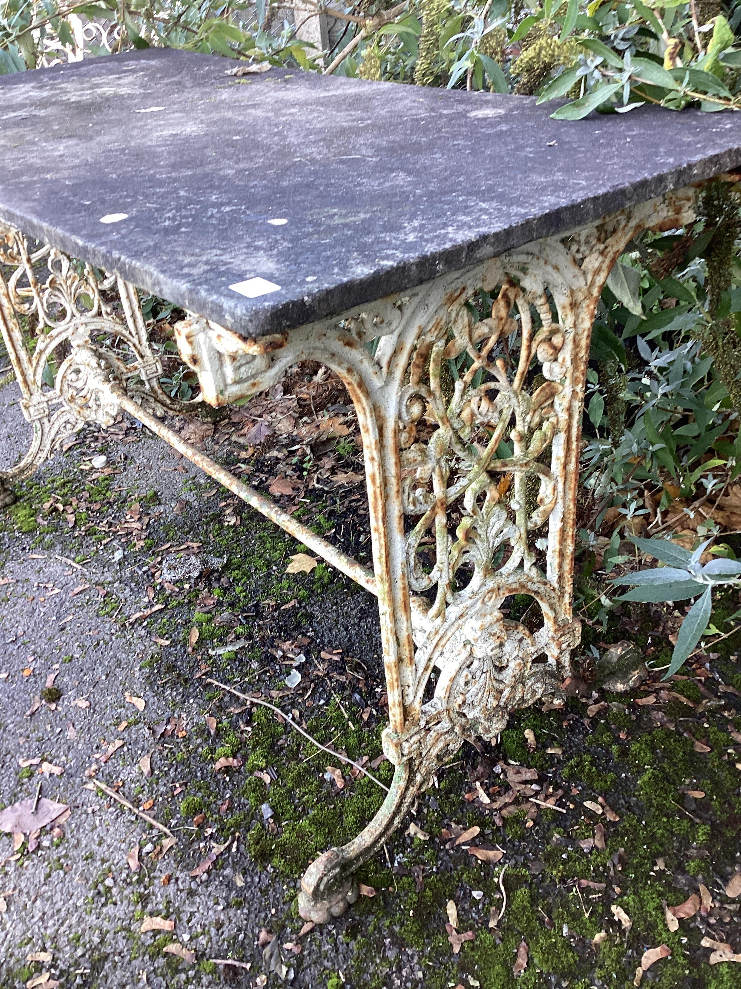 A Victorian painted cast iron garden table with weathered marble top, together with a similar table with damaged marble top, larger width 153cm, height 70cm.
